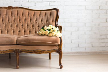 Beyaz tuğla duvarında çiçekler olan klasik rococo kanepesi.