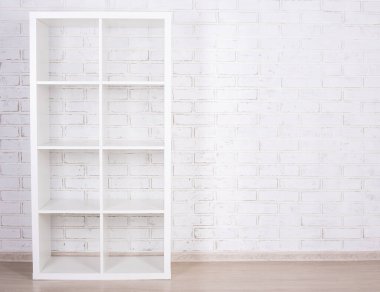 Beyaz tuğla duvarın üzerinde beyaz ahşap raf