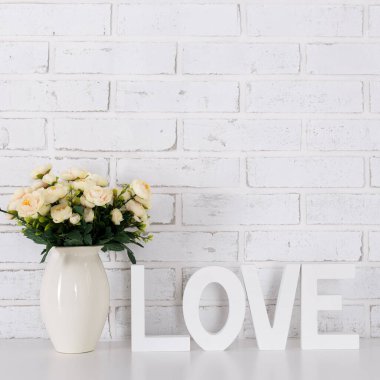 Aşk ve Sevgililer Günü konsepti - ahşap harfler aşk ve çiçekler oluşturan beyaz tuğla duvar arkaplanı