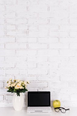 Beyaz tuğla duvarın üzerinde dizüstü bilgisayarı olan iş yeri