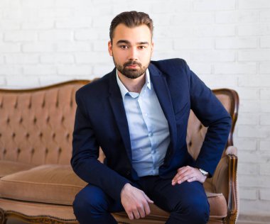 İş, zenginlik ve başarı konsepti - genç yakışıklı adam klasik koltukta oturuyor