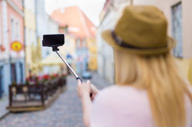 seyahat ve fotoğraf konsepti - genç kadın turist akıllı telefonuyla selfie çubuğuyla fotoğraf çekiyor