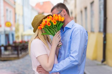 Aşk ve ilişki kavramı. Şehirde çiçeklerle öpüşen genç bir çift.