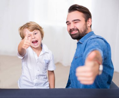 happy family portrait - young father and his cute little son thumbs up at home clipart