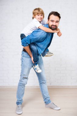 Mutlu aile portresi. Beyaz tuğla duvarın üzerinde küçük tatlı bir oğlu olan baba.