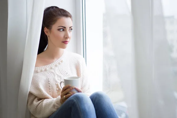 Młoda Piękna Kobieta Pije Kawę Patrzy Przez Okno — Zdjęcie stockowe