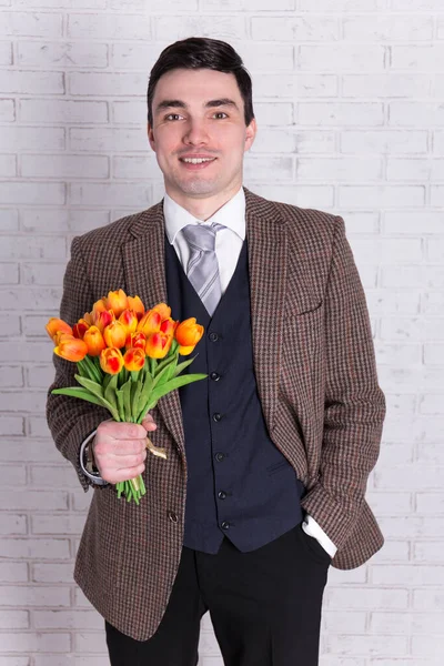 Ung Stilig Man Med Blommor Över Vit Tegelvägg — Stockfoto