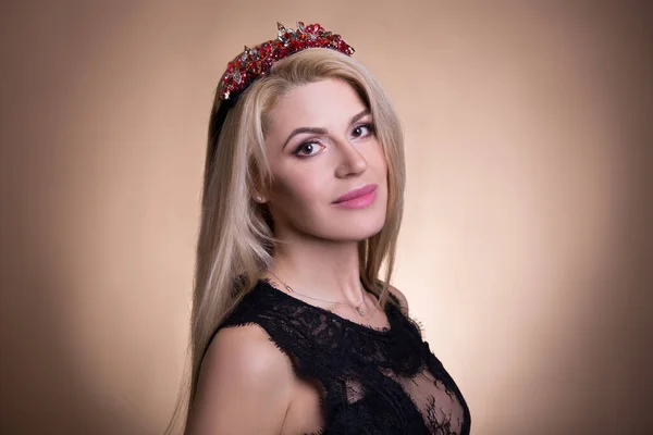 portrait of young beautiful woman in crown over beige background