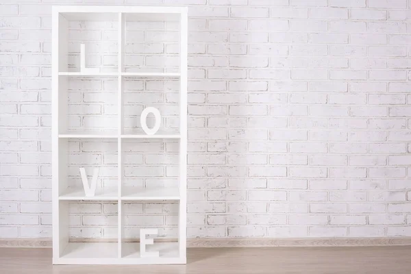 love word in wooden shelf over white brick wall background