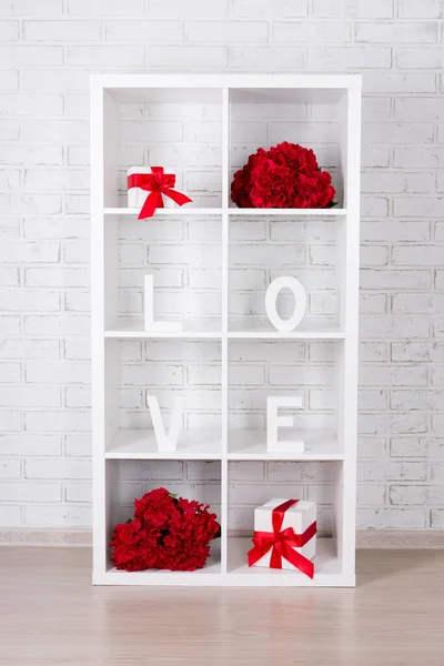 valentine\'s day concept - modern wooden shelf with flowers, gifts and word love