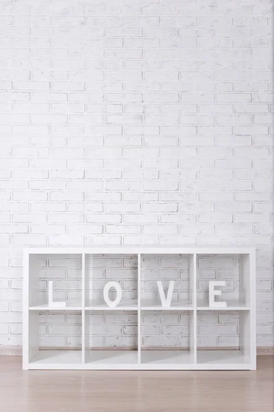 木製の手紙形成単語愛で現代棚の上に白いレンガの壁 — ストック写真