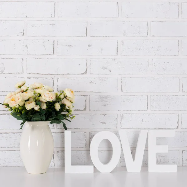 Aşk ve Sevgililer Günü konsepti - ahşap harfler aşk ve çiçekler oluşturan beyaz tuğla duvar arkaplanı