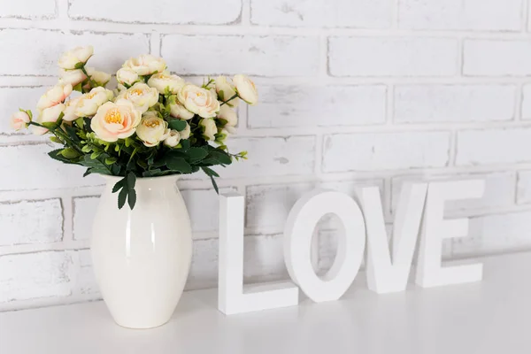 Λουλούδια Και Λευκή Ξύλινη Λέξη Αγάπη Πάνω Από Λευκό Τούβλο — Φωτογραφία Αρχείου