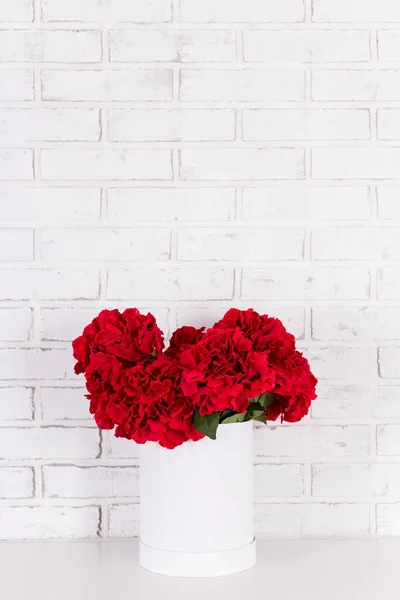 Bukiet Pięknych Czerwonych Kwiatów Wazonie Nad Białą Ceglaną Ścianą — Zdjęcie stockowe