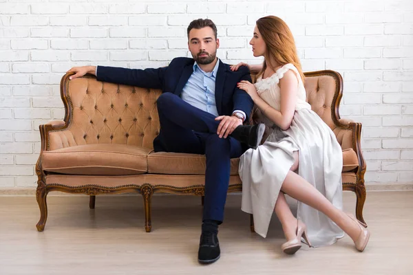 Zenginlik ve başarı kavramı. Takım elbiseli yakışıklı sakallı adam. Güzel bir kızla klasik koltukta oturuyor.