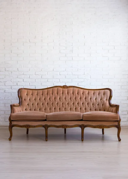 Beyaz tuğla duvarın üzerinde kahverengi eski bir kanepe