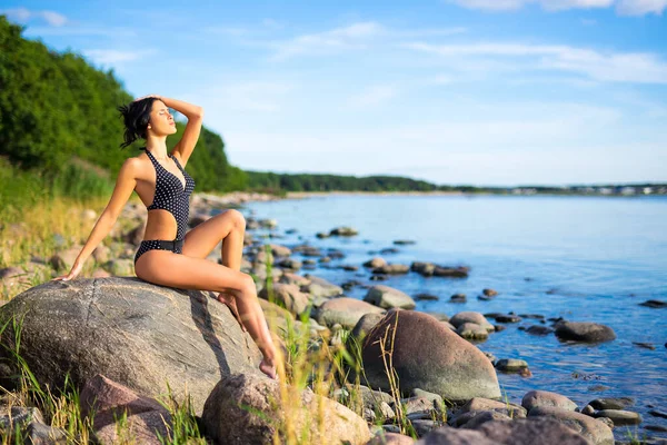 若いです美しいです女性で水着岩のビーチで日光浴 — ストック写真