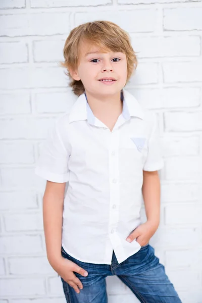 可爱小男孩在白色砖墙上摆姿势的肖像 — 图库照片