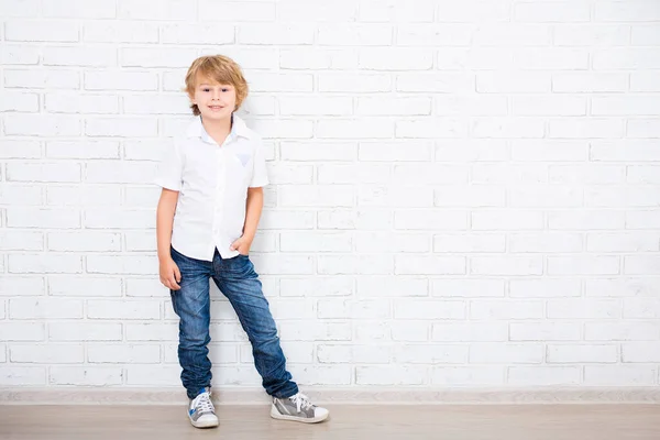 在白砖墙上摆姿势的可爱小男孩的全长肖像 — 图库照片