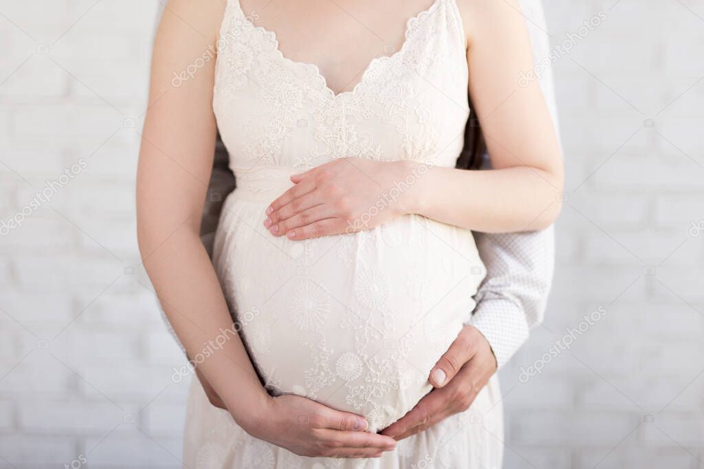 pregnant couple expecting baby with heart hands on belly over white background