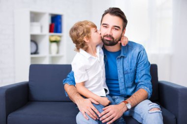 Aile ve aşk kavramı. Küçük oğlu evde babasını öpüyor.