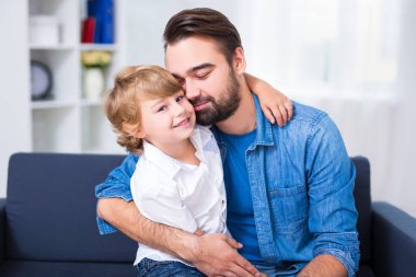 Aile hayatı. Küçük oğlunu kucaklayan genç bir baba.