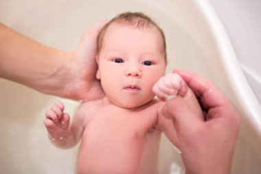 Babanın ellerinde banyo yapan şirin yeni doğmuş bebeğe.