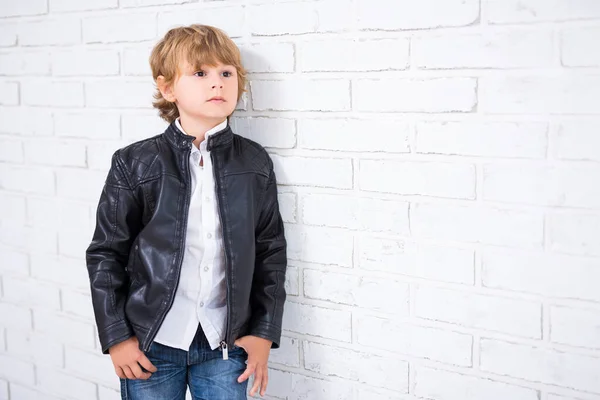 身穿皮夹克的小男孩的肖像 摆设在白色砖墙的背景上 — 图库照片
