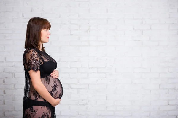 Zijaanzicht Van Zwangere Vrouw Zwart Kant Jurk Poseren Witte Baksteen — Stockfoto