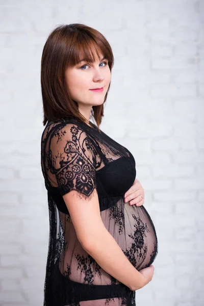 Беременная Женщина Черном Кружевном Платье Позирует Фоне Белой Кирпичной Стены — стоковое фото