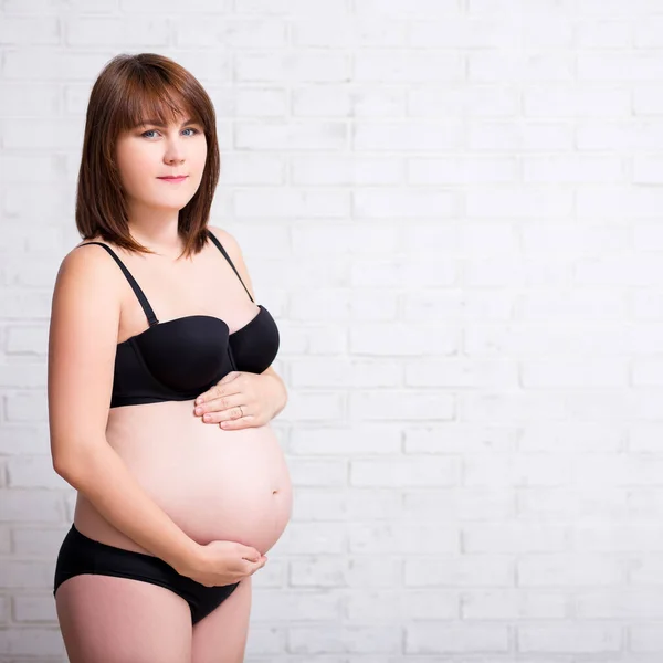 Schwangere Dessous Berühren Ihren Bauch Über Weißem Backsteinmauerhintergrund Mit Kopierraum — Stockfoto