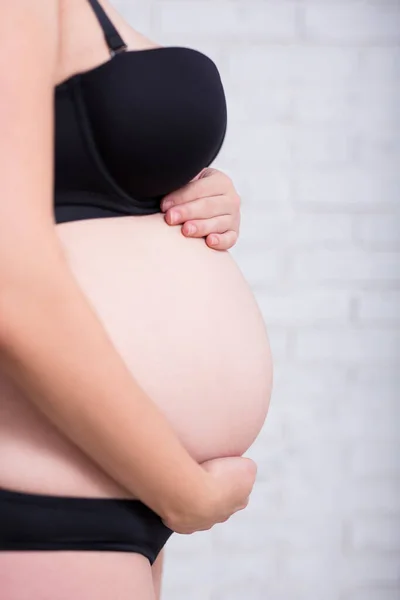 Widok Boku Zbliżenie Brzucha Kobiety Ciąży Czarnej Bieliźnie Nad Białą — Zdjęcie stockowe