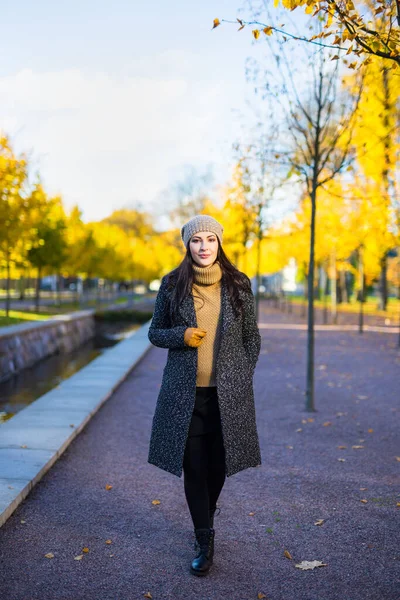 穿着保暖衣服的年轻貌美女子在秋天的公园里散步 — 图库照片
