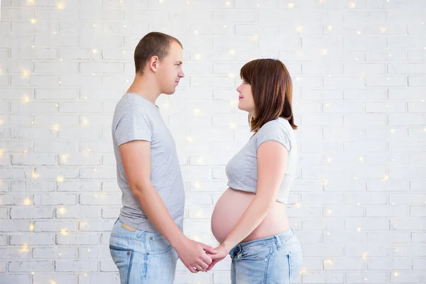 Side View Happy Pregnant Couple White Brick Wall Christmas Lights — Stock Photo, Image
