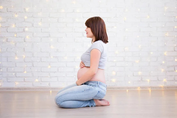 Aile Annelik Kavramı Hamile Bir Kadının Beyaz Tuğlalı Duvarın Üzerinde — Stok fotoğraf