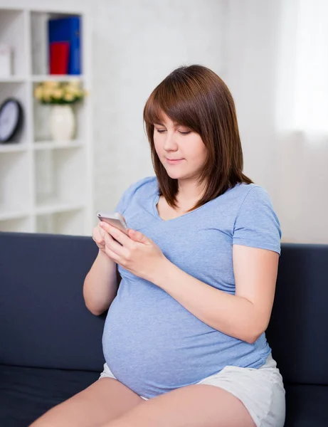 Junge Schwangere Frau Sitzt Wohnzimmer Und Nutzt Modernes Smartphone — Stockfoto