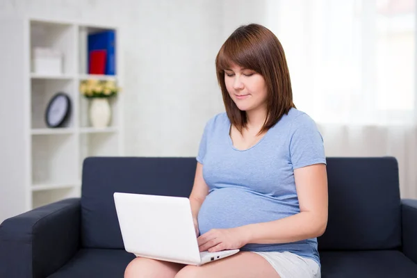 年轻漂亮的孕妇在家里用笔记本电脑 — 图库照片