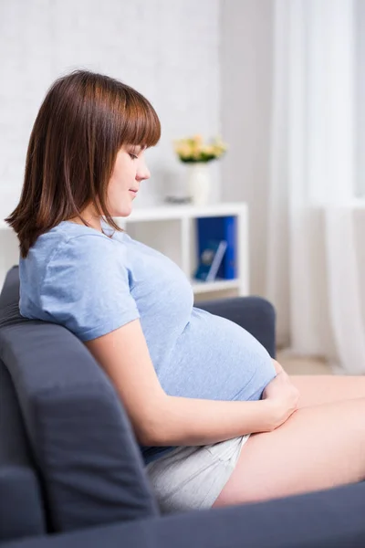 Hübsche Schwangere Frau Sitzt Wohnzimmer Und Schaut Auf Ihren Bauch — Stockfoto