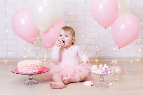 誕生日パーティーのコンセプト 面白い女の子食べるケーキレンガの壁の背景にライトとカラフルな風船 — ストック写真