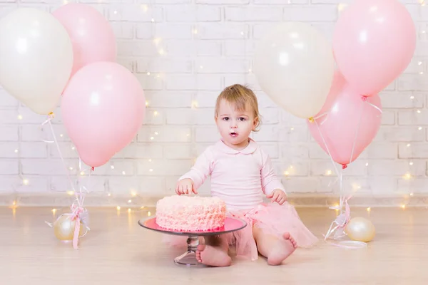 誕生日お祝い ライトとカラフルな風船でレンガの壁の背景にケーキと幸せな女の子 — ストック写真