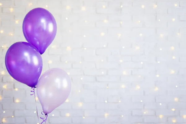 birthday party concept - purple air balloons over brick wall background with lights