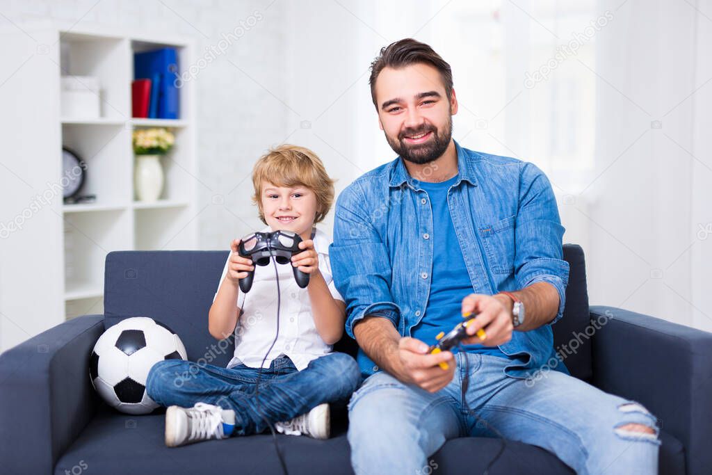 young father and little son playing video games at home