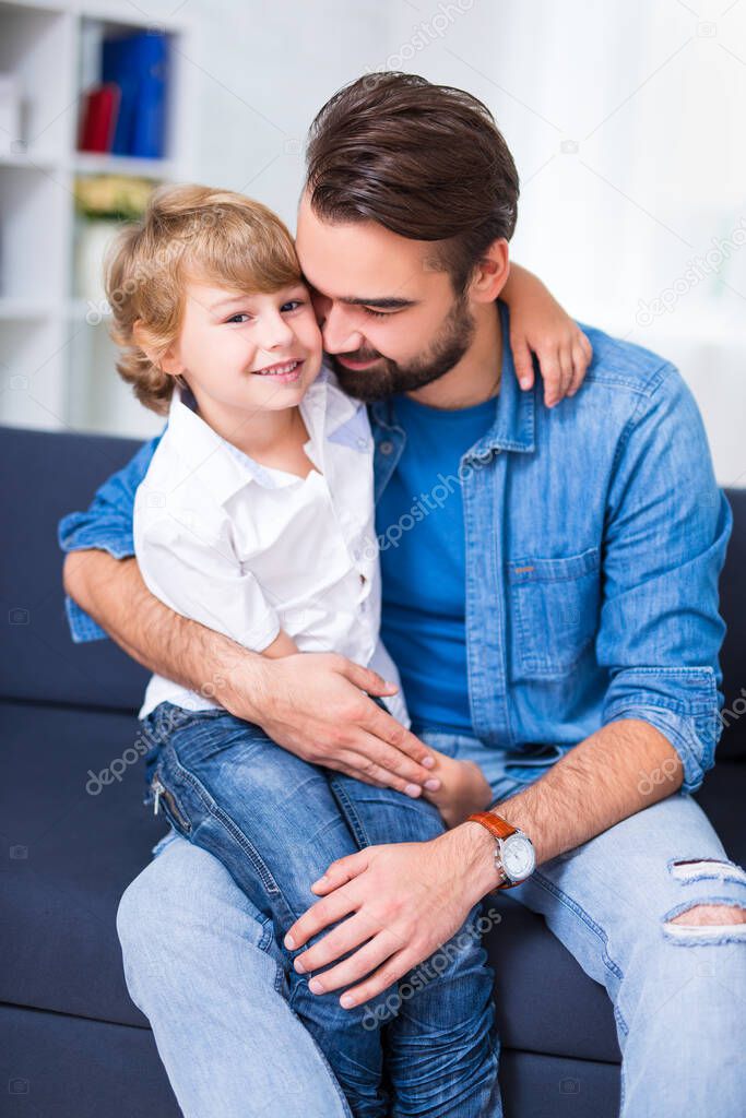 family and love concept - young father embracing his little son at home