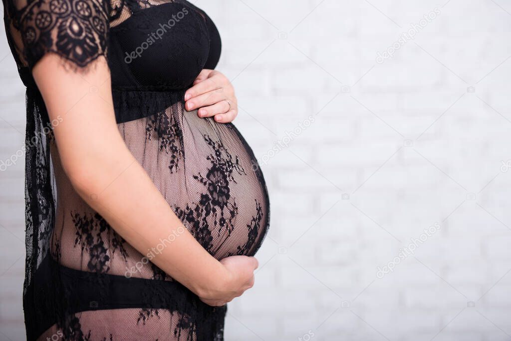 close up of pregnant woman touching her belly over white background