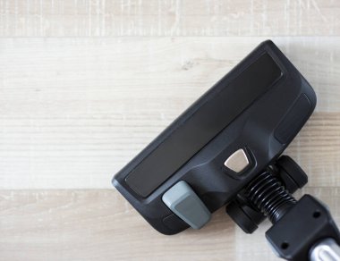 Modern elektrik süpürgesinin üst görüntüsü ahşap zemini süpürüyor