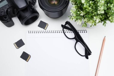 Fotoğrafçının iş yerinin üst görüntüsü - fotoğraf ekipmanları, not defteri, gözlükler ve bitki