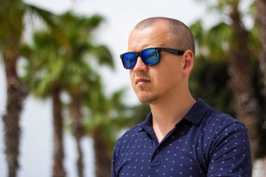 Yaz parkında palmiye ağaçlarıyla genç bir adamın portresi.