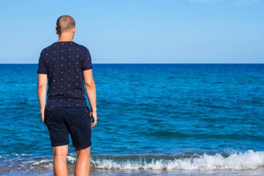 Yaz tatili konsepti. Genç ve yakışıklı bir adamın denize bakışı.