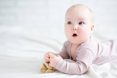 Fikir - yatakta yatıp bir şeyler düşünen küçük tatlı bir kız bebek - beyaz çarşafın üzerine kopyalama alanı