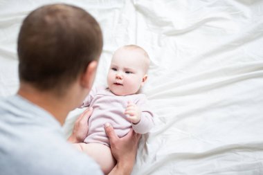 Mutlu genç baba evde tatlı bir bebekle oynuyor - beyaz çarşaf üzerine kopyalama alanı